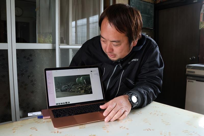 当時の写真を見ながら被害状況を説明する鈴木さん＝佐倉市