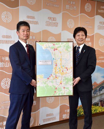 交通安全マップのパネルを掲げる井上清文理事・千葉地域担当（右）と森市長＝館山市役所
