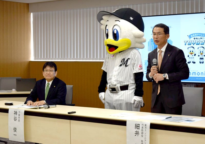 千葉市美浜区への本社移転などを発表する細井社長（右）。千葉ロッテのマスコットも駆け付けた＝２８日、同市役所
