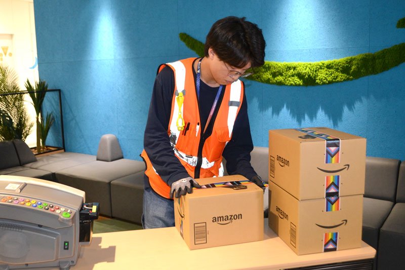 レインボーカラーの特製テープで荷物を梱包する様子＝１５日、千葉市美浜区のアマゾン千葉みなとＦＣ