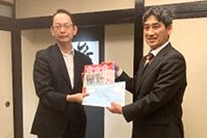 黄氏（左）に寄せ書きを手渡す松井教授