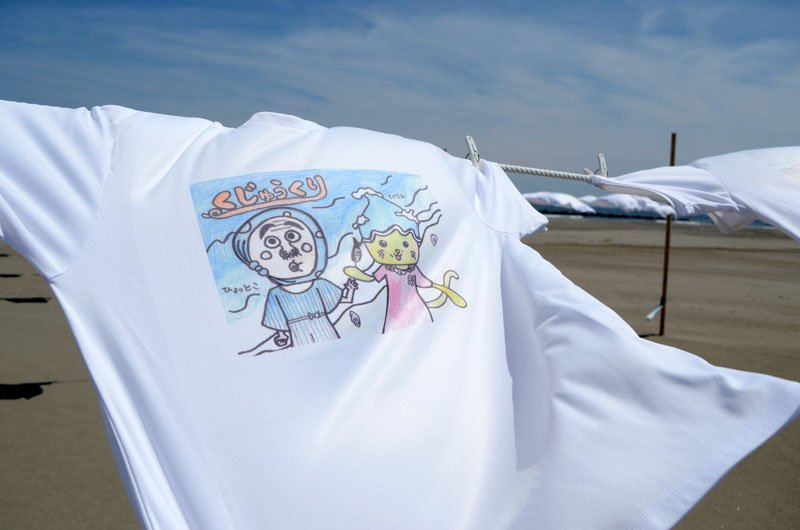 小中学生が町キャラクター「くくりん」などをデザインしたＴシャツが砂浜に展示されている＝１９日、九十九里町