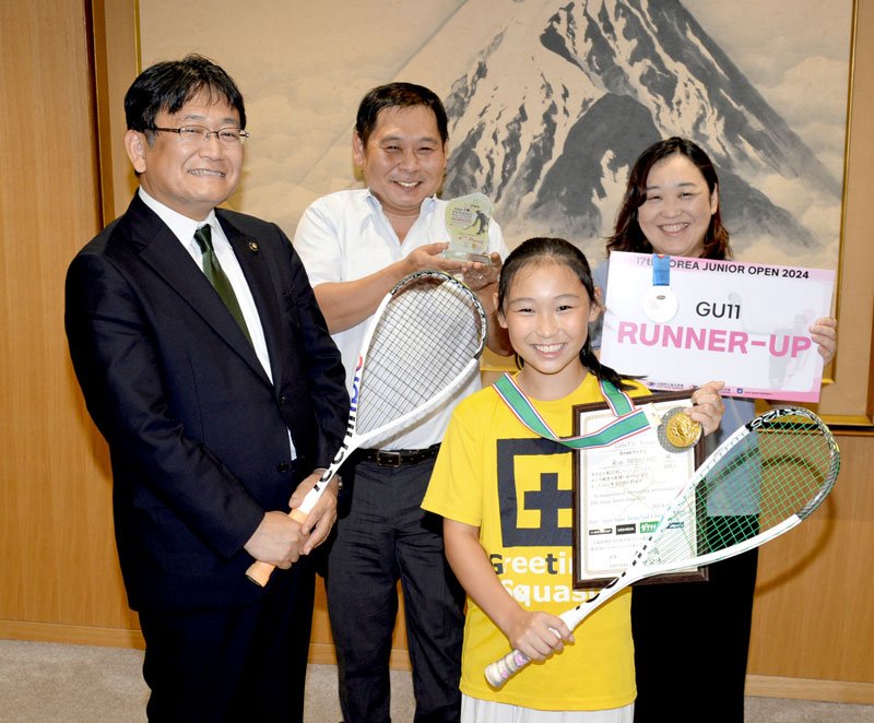 スカッシュの国際大会で初優勝し、神谷市長（左）にメダルを携えて報告した吉野莉央さん（手前）。後ろは競技生活を支える両親＝千葉市役所