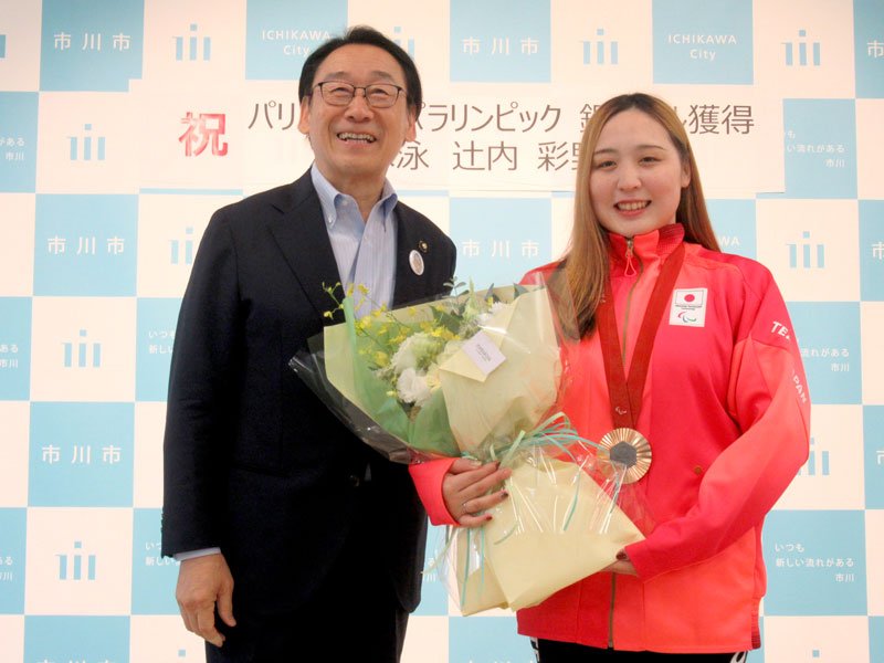 田中市長（左）から花束を贈られ笑顔の辻内選手＝３日、市川市役所