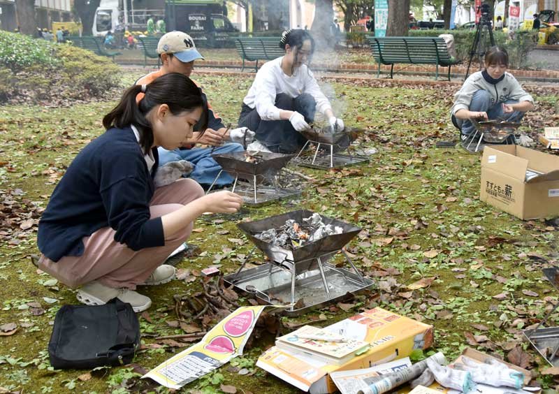 サバイバルキャンプで火起こしに挑戦する千葉商科大生＝市川市