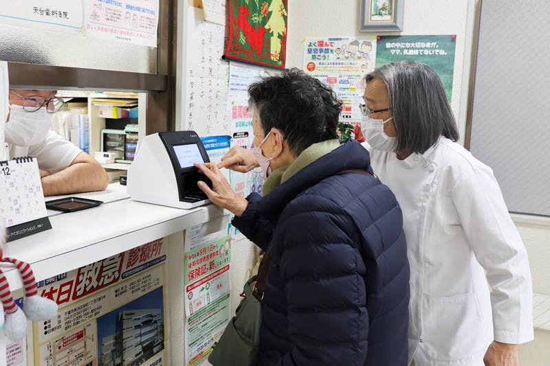 マイナ保険証の読み取り機の使い方を教わる患者＝３日午前、千葉市稲毛区