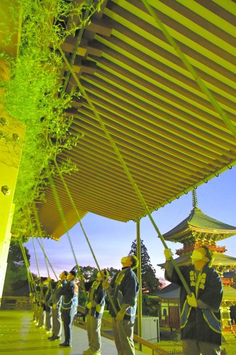 ササ竹を使って大本堂の軒下のすす払いをする成田山新勝寺の職員＝１３日、成田市