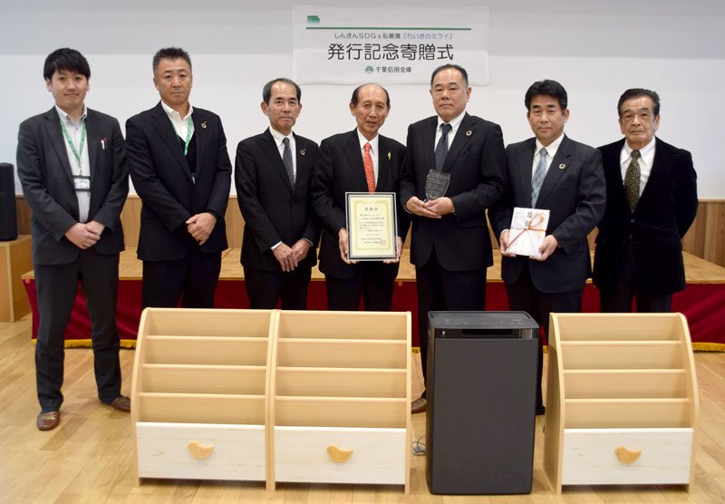 永田社長（右から３人目）と、目録を持つ伊藤理事長（同２人目）＝千葉市中央区