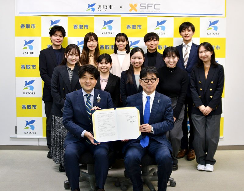 スローシティの推進などに向け協定を結んだ香取市の伊藤市長（前列左）と慶応大ＳＦＣ研究所の飯盛教授（同右）と学生たち＝香取市役所