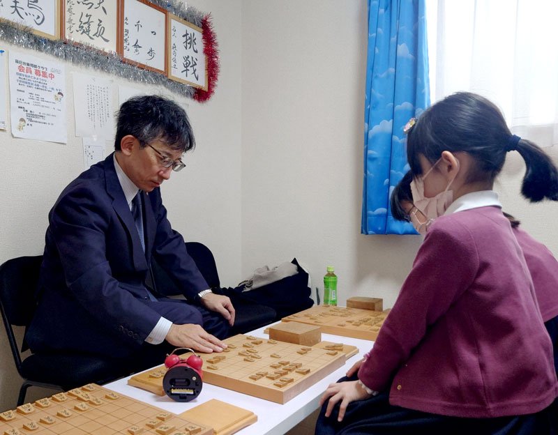 小学生の姉妹と指導対局する佐藤九段（左）＝市原市の辰巳台東将棋クラブ