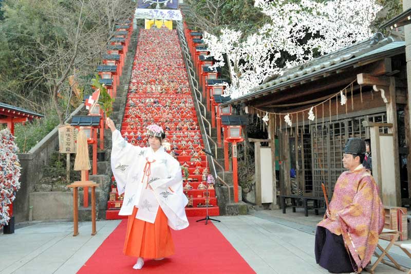 かつうらビッグひな祭りの成功祈願祭で、石段に飾られたひな人形を前に舞を披露する巫女＝９日、勝浦市