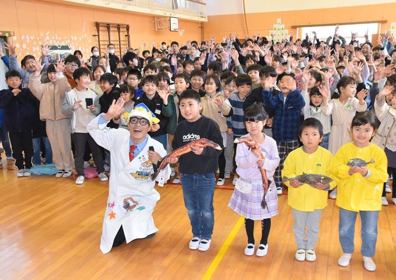 市立館山小の児童らに「おさかなぬいぐるみ」を手渡したさかなクン（左）＝館山市

