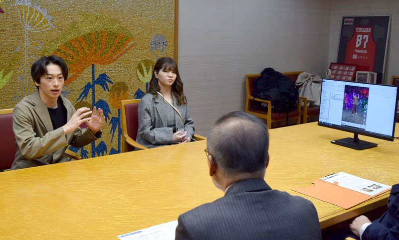 映像を見ながら松戸市長（手前）にダンスの説明をする龍さん（左）＝船橋市役所