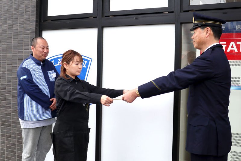 戸村署長（右）から感謝状を受け取る菊森さん（中央）＝千葉市緑区の「ローソン土気駅前店」