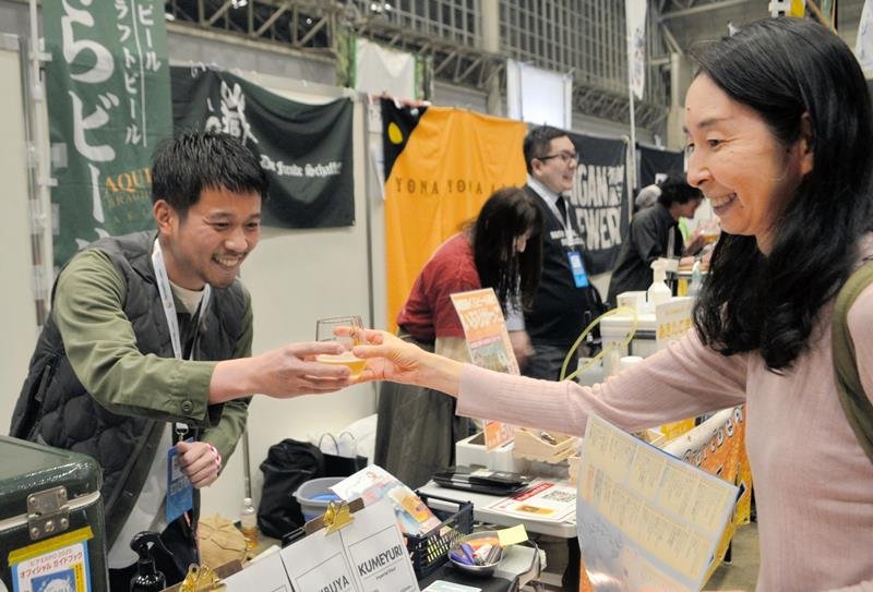 幕張メッセで開かれたビアＥＸＰＯで来場者にビールを手渡す出展者＝千葉市美浜区