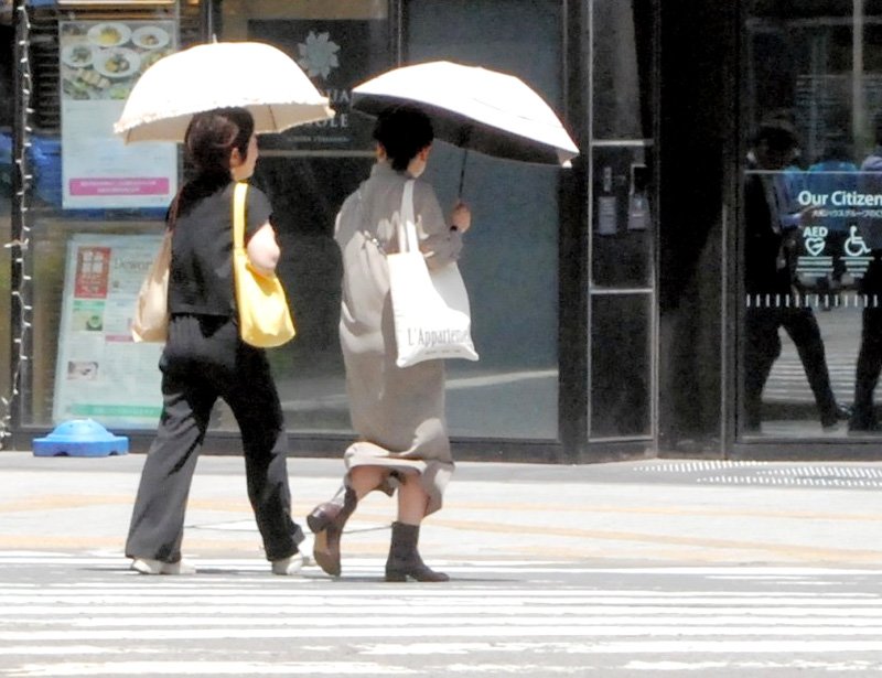 暑さの中、日傘を差す人たち＝２０日正午過ぎ、千葉市中央区