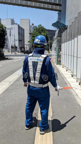 電動ファン付きの空調服を着て仕事をする交通誘導員＝１７日、千葉市中央区