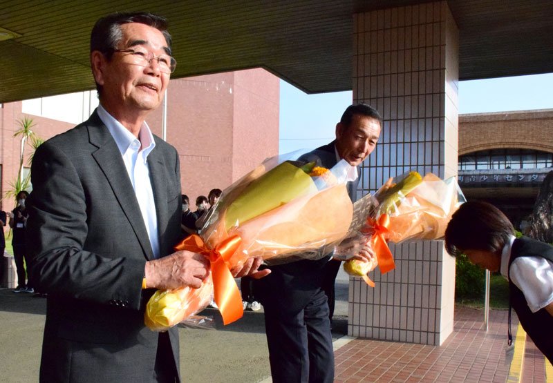 職員から花束を受け取り、町役場を後にする石井氏（左）＝１８日、白子町