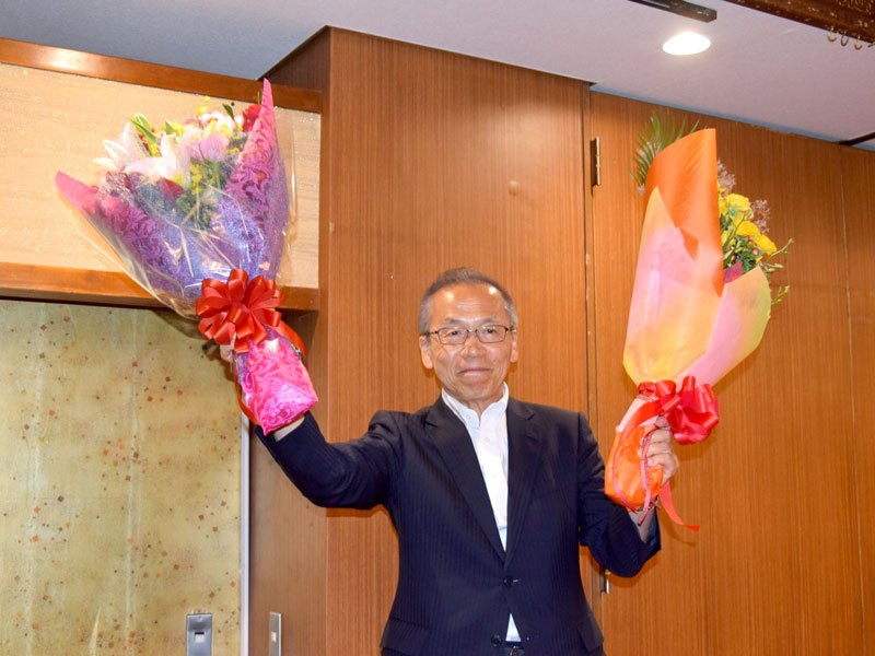 ４回目の当選を果たし、支持者から贈られた花束を掲げる松戸氏＝２２日夜、船橋市