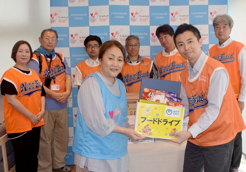 フードバンクちばの担当者へ食料品を寄贈する野寄企画総務部長（前列右）＝千葉市中央区