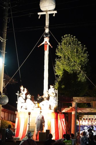 鳥居を超える高さの柱に登り妙技を披露する演者＝２７日夜、旭市
