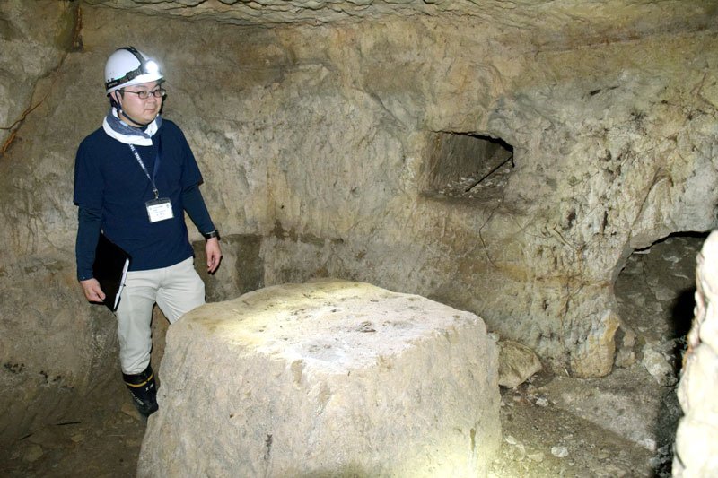 地下壕の奥にある重機関銃の台座跡を説明する江沢一樹学芸員＝一宮町