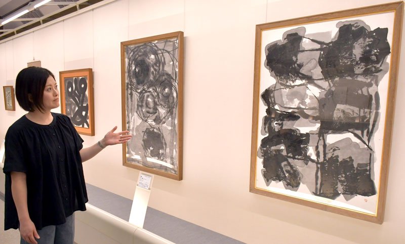 「街」（右）など香川春蘭の作品を紹介する谷本さん＝成田市