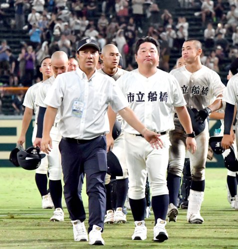 明豊戦後、一塁側応援席へのあいさつを終えてベンチに戻る市船橋の野田部長（左手前）。中央は海上監督＝９日、甲子園