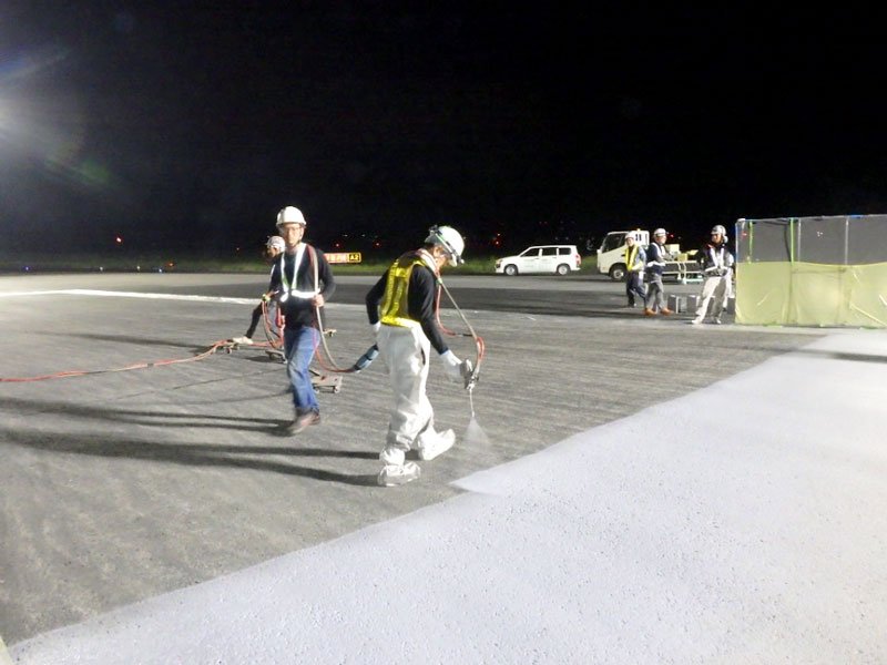 航空機がわだちにはまって立ち往生が相次いだ成田空港の誘導路で遮熱性の高い舗装を施工する作業員ら＝７日未明、成田市（ＮＡＡ提供）