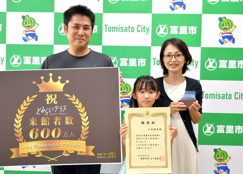富里市図書館の来館者６００万人目となった戸村さん（中央）とその両親＝同市