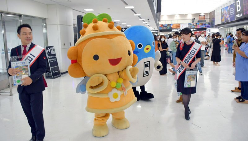 成田空港で外国人観光客らに交通安全を呼びかけたＪＡＬの地上係員ら。成田市観光キャラクター「うなりくん」と芝山町キャラクター「しばっこくん」も一行に加わった＝成田市