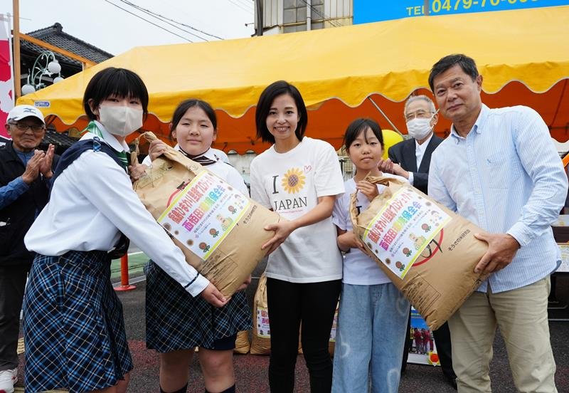 福島復興支援のヒマワリの種が入った袋を授受する関係者＝匝瑳市
