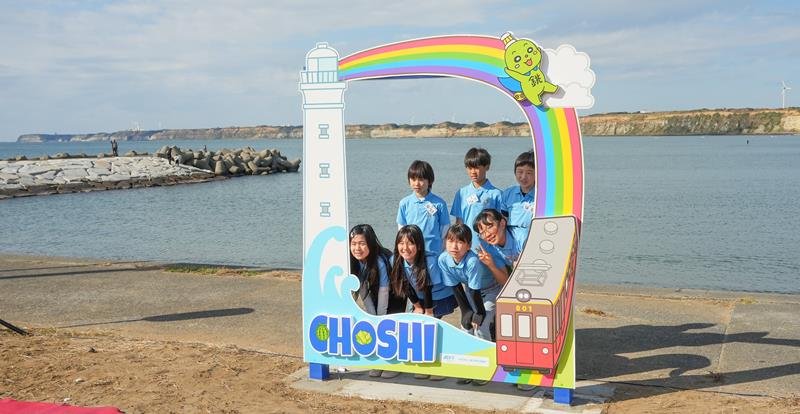 青い海と屏風ケ浦を背景にしたフォトフレームで写真に収まる小学生＝銚子市
