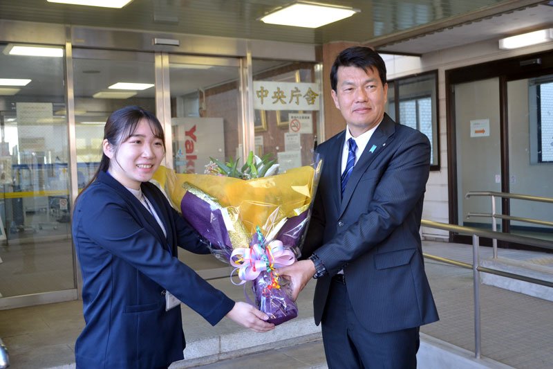 町役場に初登庁し、花束を受け取る金塚町長（右）＝８日、酒々井町役場