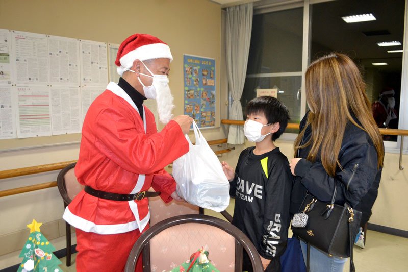 クリスマスチキンを子どもたちに手渡す岩渕社長（左）＝佐倉市