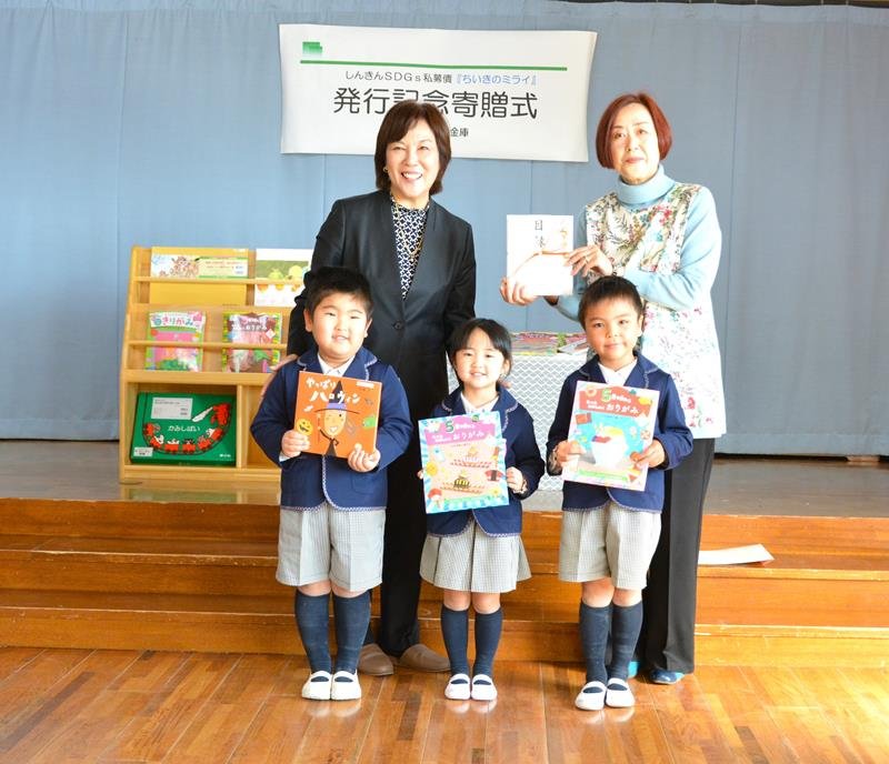 宮寺社長（後列左）と目録を持つ雨宮理事長（後列右）と寄贈された絵本を持つ園児＝市原市

