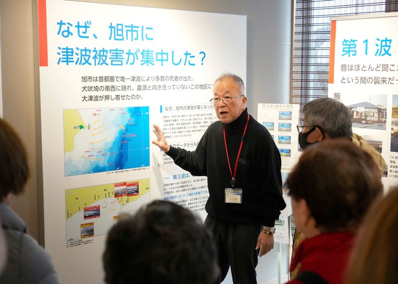 来館者に旭市の津波被害を説明する佐久間さん＝旭市防災資料館
