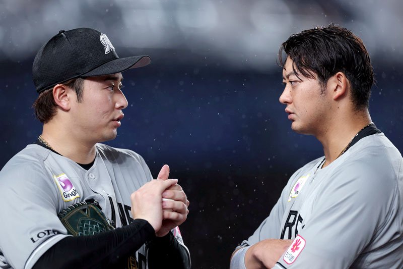 雨が降る中、真剣な表情で話し合う横山（左）と捕手の佐藤