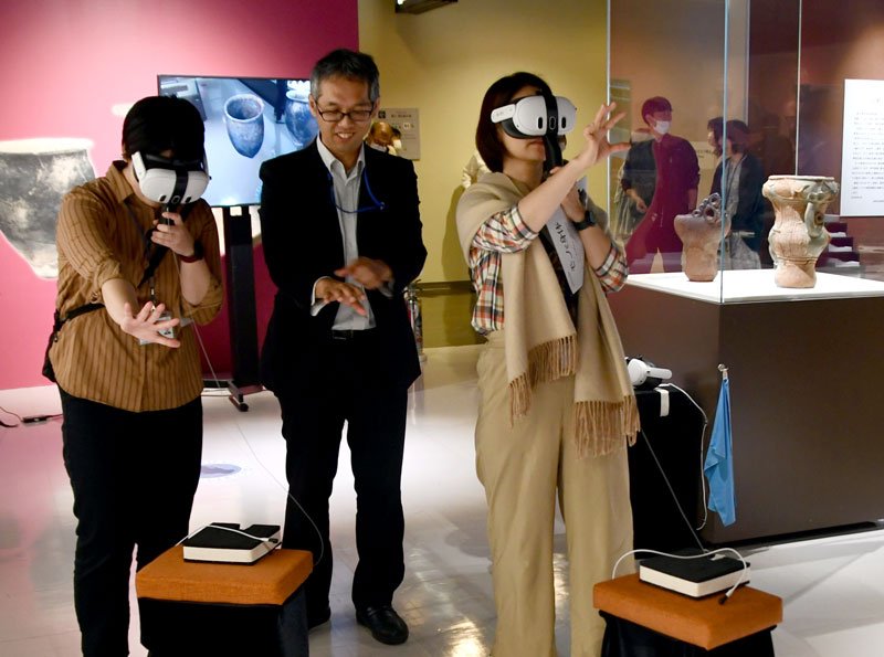 ゴーグルを付けＶＲを体験する展示解説会参加者