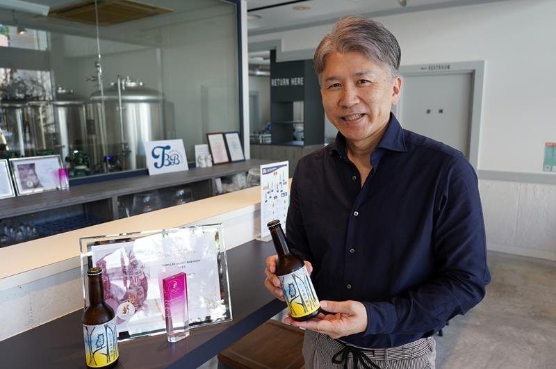 「ヒノキ森の賢者」の瓶ビールを持つスリラービーチブルワリーの笠倉さん＝勝浦市



