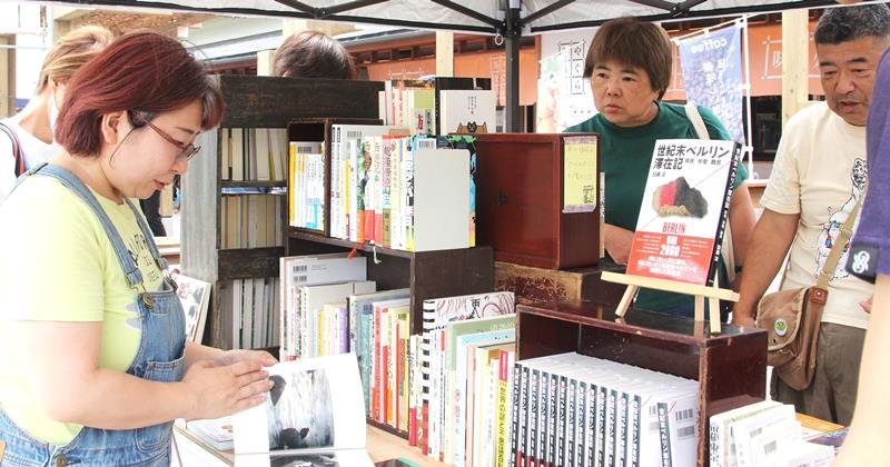 道の駅きょなん観光物産センターの「やぐら茶屋」で開かれた「きょなんぶっく市」で、お気に入りの本を探す利用客と店員ら＝鋸南町
