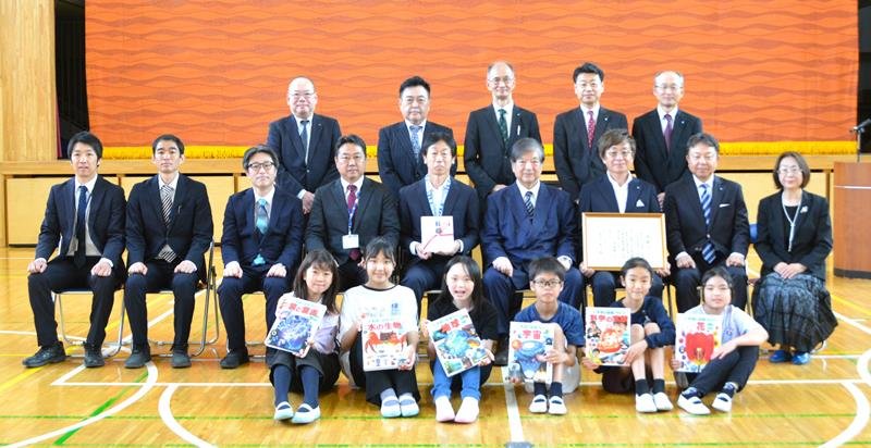 船橋法人会、大同生命保険関係者らと、寄贈された図鑑を持つ生徒ら＝船橋市
