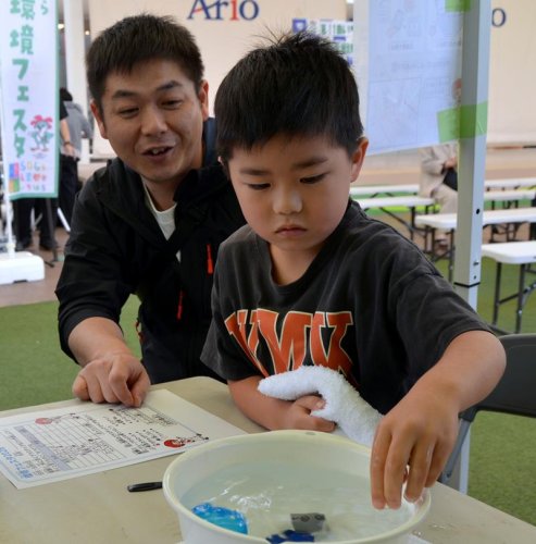 住友化学千葉工場のブースで浮力実験にチャレンジする親子＝アリオ市原
