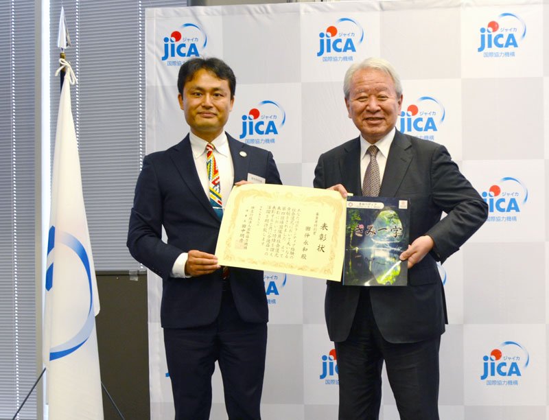 田中理事長（右）から表彰状を受け取った田仲さん＝８日、東京都