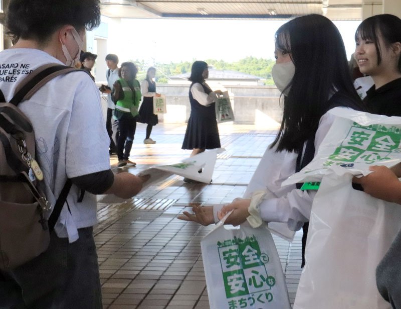 痴漢や盗撮の撲滅を訴えるチラシなどが入った袋を配布する土気高生ら＝千葉市緑区のＪＲ鎌取駅構内