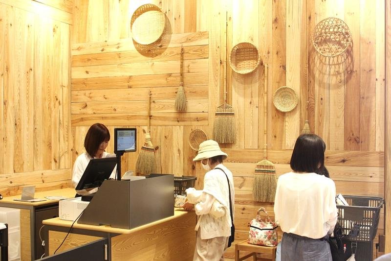 木材を用いた内装に、竹を使ったかごやほうきを展示したレジ＝１２日、館山市

