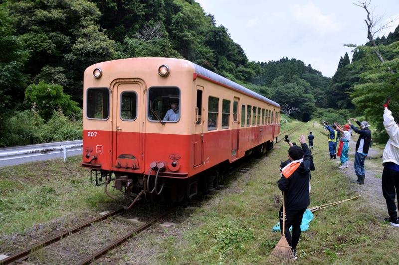 除草作業の手を休め小湊鉄道の乗客らに手を振る参加者＝１３日、市原市