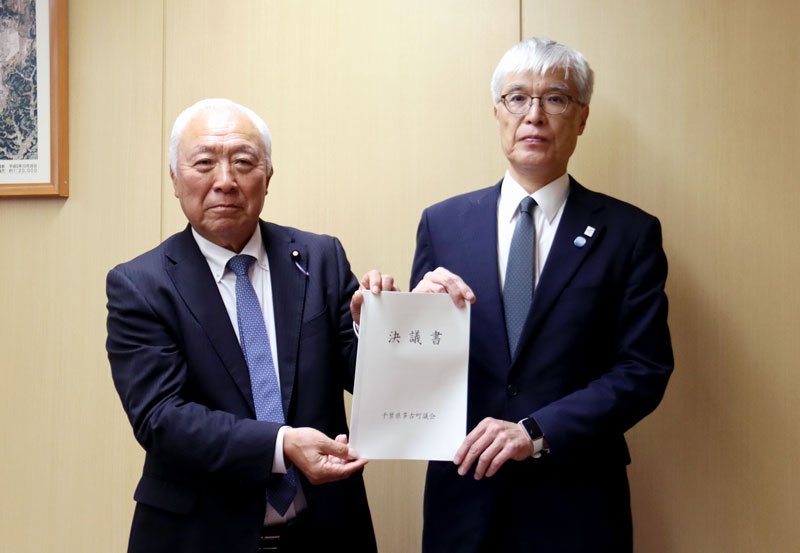 ＮＡＡの藤井社長（右）に決議書を手渡す多古町議会の鵜沢議長＝成田市のＮＡＡ本社（多古町提供）