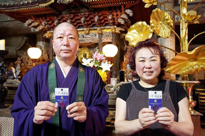 祈とう後のピンバッジお守りを手にする、清水寺の井上住職（左）と妻の恵津子さん＝いすみ市