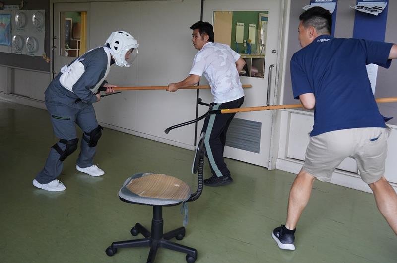 学校に侵入した不審者役の勝浦署員（左）に刺股を使って対応する教員＝大多喜町
